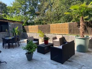 a patio with chairs and tables and a palm tree at Maison d'hôtes Zen in Arbin