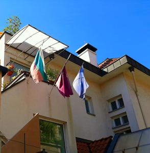 trois drapeaux suspendus sur le côté d'un bâtiment dans l'établissement Guest House Diel, à Veliko Tarnovo