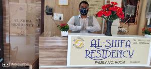 a man wearing a gas mask standing behind a sign at AL Shifa Residency in Mumbai