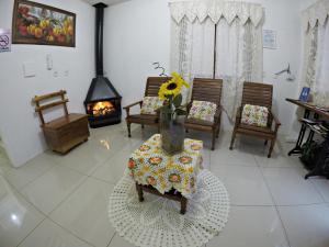 una sala de estar con chimenea y una mesa con un jarrón de flores en Pousada Justen, en Gramado