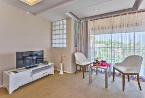 sala de estar con TV, 2 sillas y mesa en RA Resort Otel en Kucukkuyu