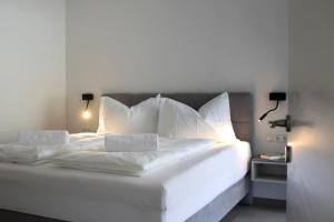 ein weißes Bett mit weißer Bettwäsche und Kissen in der Unterkunft CasaLuNa in Appiano sulla Strada del Vino