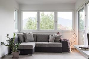 un sofá en una sala de estar con ventanas en CasaLuNa, en Appiano sulla Strada del Vino