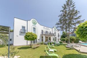 un grande edificio bianco con cortile attrezzato con sedie di Hotel Hubertus a Söchau