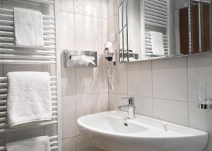 a bathroom with a sink and a mirror and towels at Hotel Ilbertz Garni in Cologne