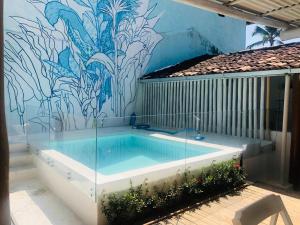 a swimming pool in front of a wall with a mural at Pousada Angatu Arraial - Rua mucugê in Arraial d'Ajuda