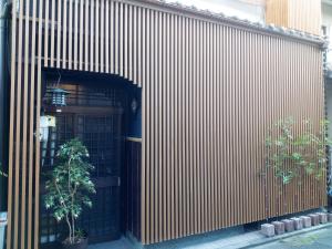 ein Gebäude mit einer Tür und einem Baum davor in der Unterkunft Kyoto Villa Kotone in Kyoto