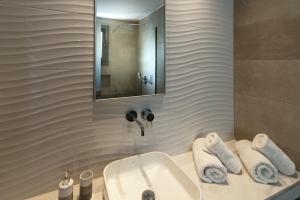 a bathroom with a sink and a mirror and towels at Zoes Hotel & Suites in Faliraki