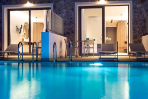 a swimming pool in a hotel with chairs and a table at Zoes Hotel & Suites in Faliraki