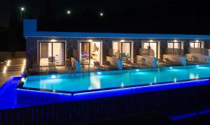 una piscina por la noche con luces azules en Zoes Hotel & Suites en Faliraki
