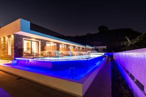 a swimming pool lit up at night with purple lights at Zoes Hotel & Suites in Faliraki
