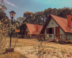 una pequeña casa con techo rojo en Pousada Vila Lubia - Chalés Monte Verde en Monte Verde