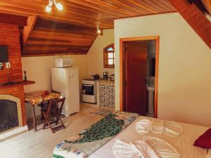 a room with a bed and a kitchen with a fireplace at Pousada Vila Lubia - Chalés Monte Verde in Monte Verde