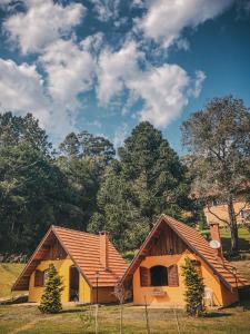 una casa en un campo con árboles en el fondo en Pousada Vila Lubia - Chalés Monte Verde en Monte Verde