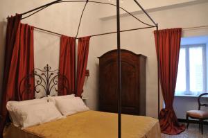 a bedroom with a canopy bed with red curtains at Casa Pagliano in Noli