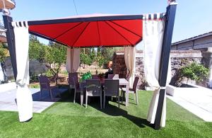 a table and chairs under a red umbrella on grass at Le Casette di Nonna Rosa in Fontanarossa Catania Airport in Catania