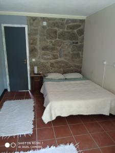 a bedroom with a bed and a stone wall at Stone Farm Hostel in Felgueiras