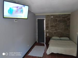 a bedroom with a bed and a flat screen tv at Stone Farm Hostel in Felgueiras
