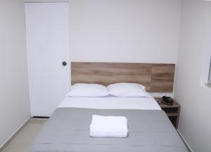 a bedroom with a bed with two towels on it at Hotel Kusnaya in Piura