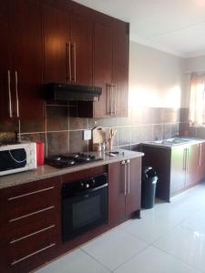 a kitchen with wooden cabinets and a stove top oven at Tumi's Home away- 3 Bedroom in Witbank