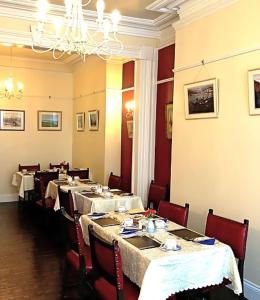 a dining room with tables and chairs and a chandelier at Melrose Guest House in Douglas