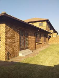 a brick building with a porch and a lawn at Tumi's Home away- 3 Bedroom in eMalahleni