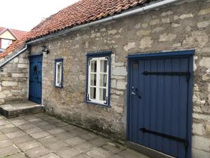a stone building with blue doors and a window at Kauba 6a apartment in Kuressaare