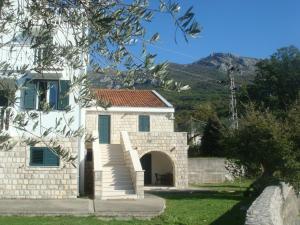 a stone house with a gate and a building at Apartmani Dragović in Sveti Stefan