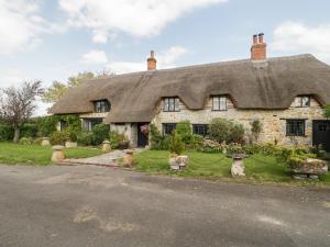 una vecchia casa in pietra con tetto di paglia di The Barn at Rapps Cottage a Ilminster