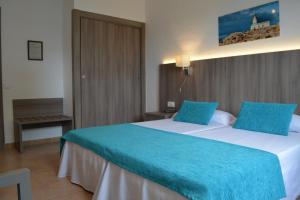 a hotel room with two beds with blue sheets at Hotel del Almirante in Es Castell