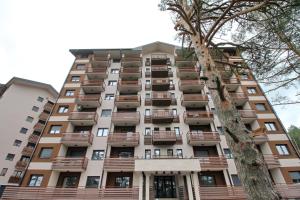 ein hohes Apartmenthaus mit Balkonen und einem Baum in der Unterkunft Vila Pekovic green-Apartman PAMA in Zlatibor
