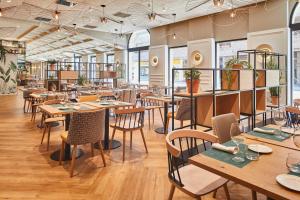 a restaurant with wooden tables and chairs and windows at Silken Ciudad de Vitoria in Vitoria-Gasteiz