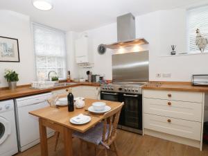 una cocina con mesa de madera y una cocina con armarios blancos. en 2B Cavendish Villas en Buxton