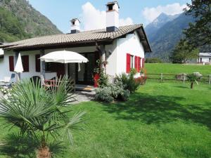 a white house with red doors and a grass yard at Casa Marco in Brione