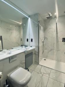 uma casa de banho branca com um chuveiro e um WC. em Dean Park Hotel em Kirkcaldy
