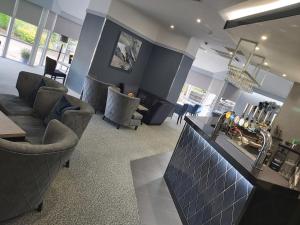 uma sala de estar com cadeiras e um bar num quarto em Dean Park Hotel em Kirkcaldy