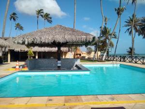 un complejo con una piscina y una cabaña de paja en Eco Paradise Temporada Aconchegante - Joana Vasconcelos, en Cumbuco