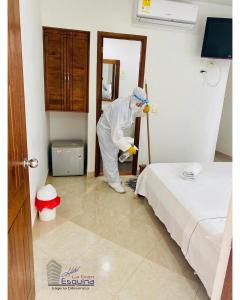 Ein Mann putzt ein Zimmer mit einem Bett in der Unterkunft Hotel La Gran Esquina in Puerto Boyacá