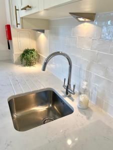 a stainless steel sink in a kitchen with white tiles at Monart Stylish City Centre Apartment, 2 Bed, sleeps 6 in Perth