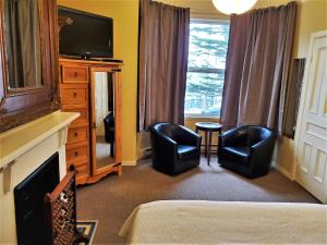 a hotel room with two chairs and a television at Abba Inn Guest House in St. John's
