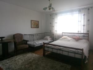a bedroom with two beds and a chair and a window at Wakacje u Babci Krysi in Górno