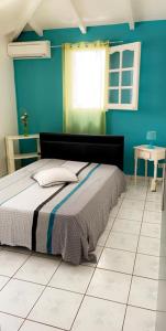 a bedroom with a bed and a blue wall at Villa Marine in Sainte-Anne