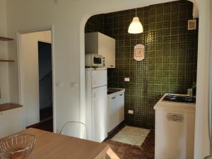 a small kitchen with a white refrigerator and green tiles at Verdolina - By Ligooria in Pietra Ligure
