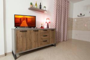 telewizor z płaskim ekranem siedzący na szczycie drewnianego centrum rozrywki w obiekcie Casa vacanza da Marisa w mieście Partinico