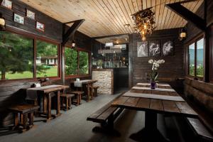 a restaurant with wooden tables and benches and windows at Aytau Sporting-Hotel in Chemal