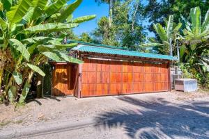 un garage en bois avec une porte rouge sur une route dans l'établissement AroCocles (Lucía), à Cocles