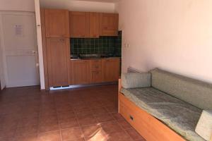 a kitchen with wooden cabinets and a couch in a room at Moriani-Plage : Résidence en bord de mer in San-Nicolao