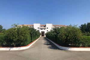 a white building with bushes in front of a driveway at Moriani-Plage : Résidence en bord de mer in San-Nicolao