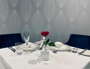 un tavolo con una rosa in un vaso bianco sopra di Dean Park Hotel a Kirkcaldy
