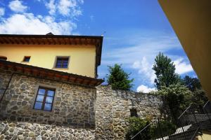 a stone building with a clock on the side of it at Borgo I Tre Baroni - Spa Suites & Resort in Poppi